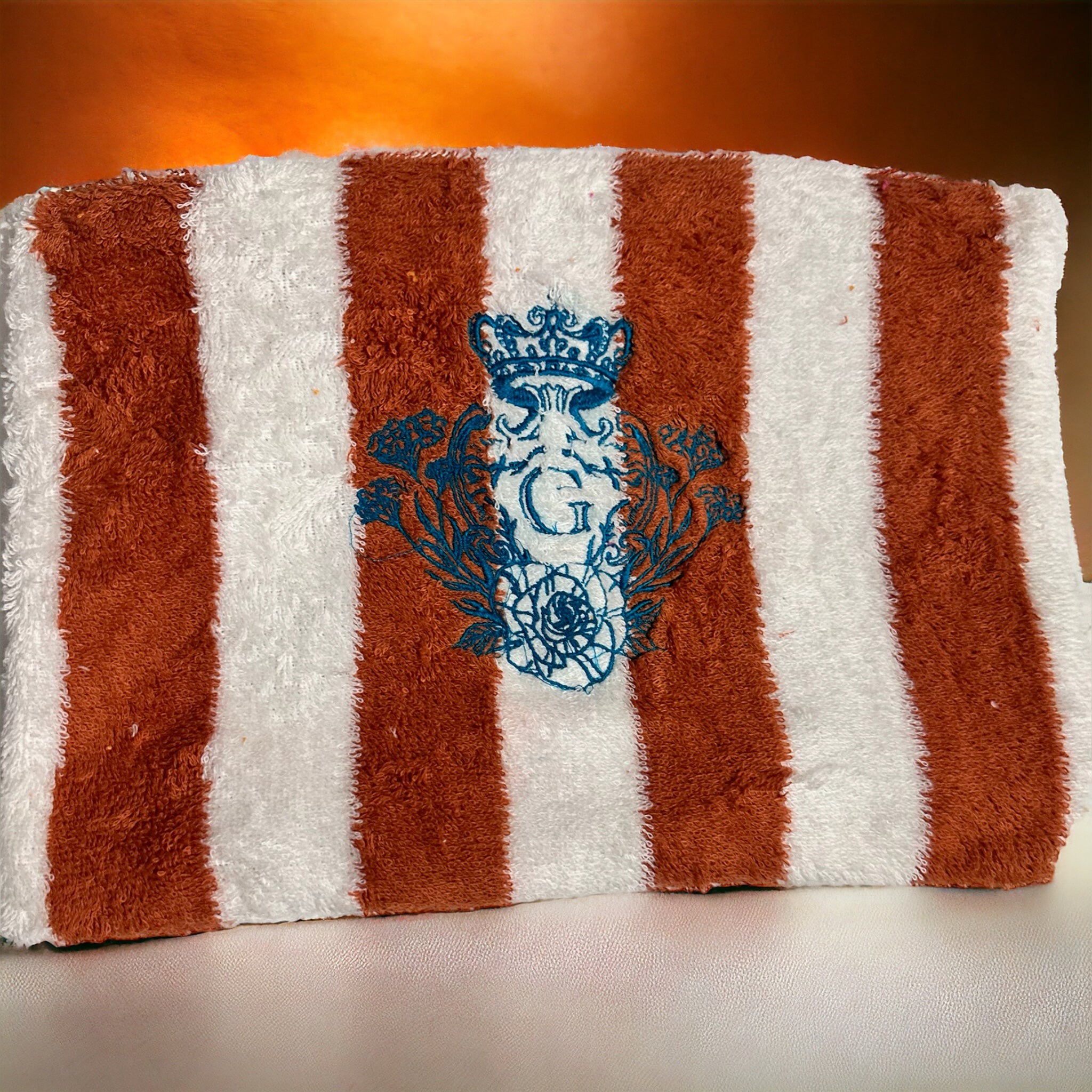 Pochette en éponge rayé terracotta(blanc et orange) intérieur en cretonne et son logo Bleu